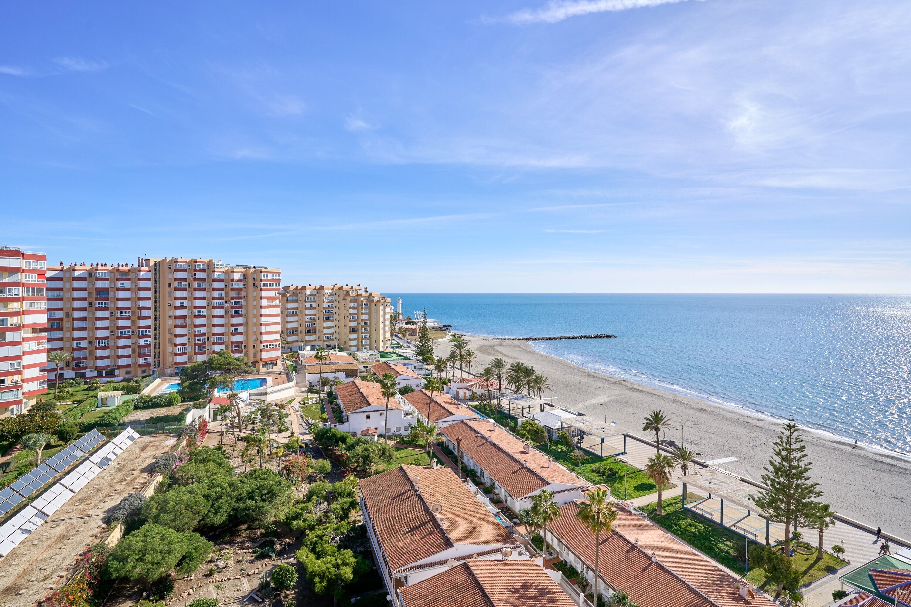 A coastal hotel with multiple buildings, a beach, and a clear sky.