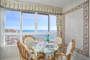 A dining area with a table set for four, a view of the beach, and a decorative border on the wall.
