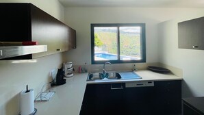 A compact kitchen with a window, a coffee maker, and a dish rack. - Holiday Home "Villa Camacho xxvii" with Sea View, Pool & Wi-Fi (Arco da Calheta)