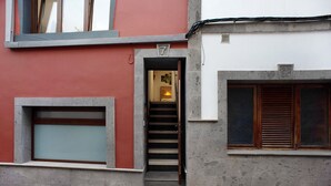 A building with a red facade, a staircase leading to an interior, and a window with wooden shutters. - Vacation 'Jardin Cardona' with Wi-Fi (Arucas)