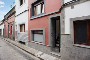 Una hilera de edificios con fachada de piedra, una puerta visible y una ventana.