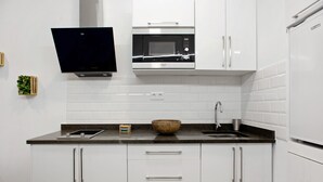 A modern kitchen with white cabinets, a microwave, a sink, and a flat-screen TV mounted above the counter. - Vacation 'Jardin Cardona' with Wi-Fi (Arucas)