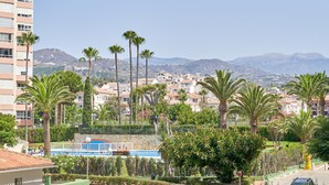 A residential area with a swimming pool, palm trees, and a view of mountains.