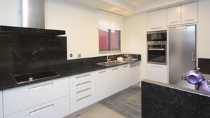 Een moderne keuken met witte kasten, zwarte aanrechtbladen, roestvrijstalen apparatuur en een raam boven de gootsteen.