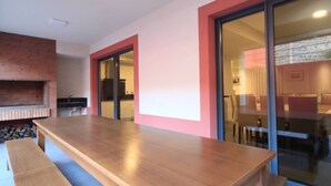 Een moderne keuken met een tegelwand van baksteen, een houten eettafel en een glazen deur naar een eetgedeelte.