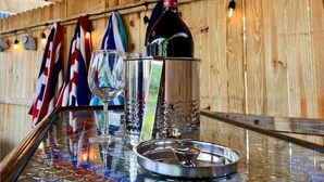 En bardisk med ett träpanelat tak, en vinflaska, glas och ett bricka med kapsyler. Flaggor hänger på väggen.