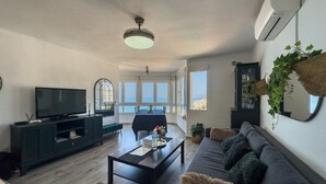 A living room with a TV, sofa, coffee table, and a dining area with a view. - Apartment "Vistas Playa Torrox A73" with Sea View, Shared Pool and Wi-Fi (Torrox)