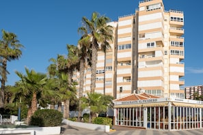 A multi-story hotel with balconies, a restaurant named 'RESTAURANTE EL PICADERO,' and palm trees in the foreground.