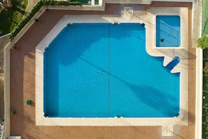 Uma piscina retangular grande com um trampolim e uma piscina menor no canto.