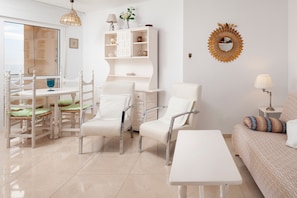 Un salon moderne avec un canapé blanc, une table à manger avec des chaises, un meuble blanc et un miroir décoratif accroché au mur.
