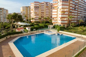 A swimming pool surrounded by greenery and residential buildings.