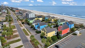 Zona residencial costera con casas coloridas, una playa y un estacionamiento.