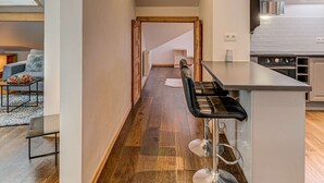 Una cocina moderna con una isla central, suelo de madera y vista a un salón.