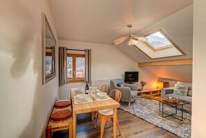 A cozy loft-style room with a dining area, a sofa, and a TV.