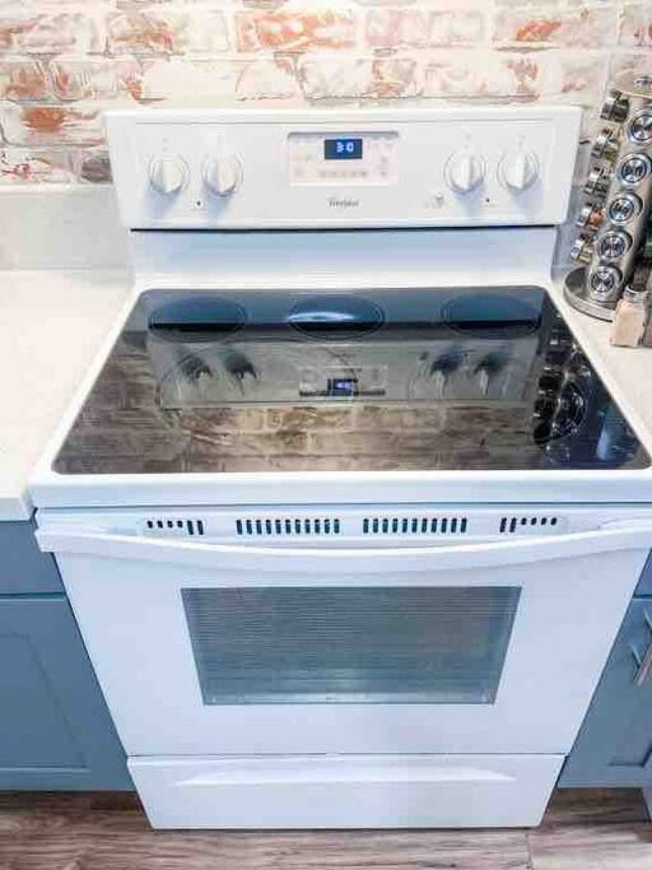 Une cuisine blanche dotée d’un four et d’une cuisinière encastrés, avec un écran numérique et des boutons de commande.