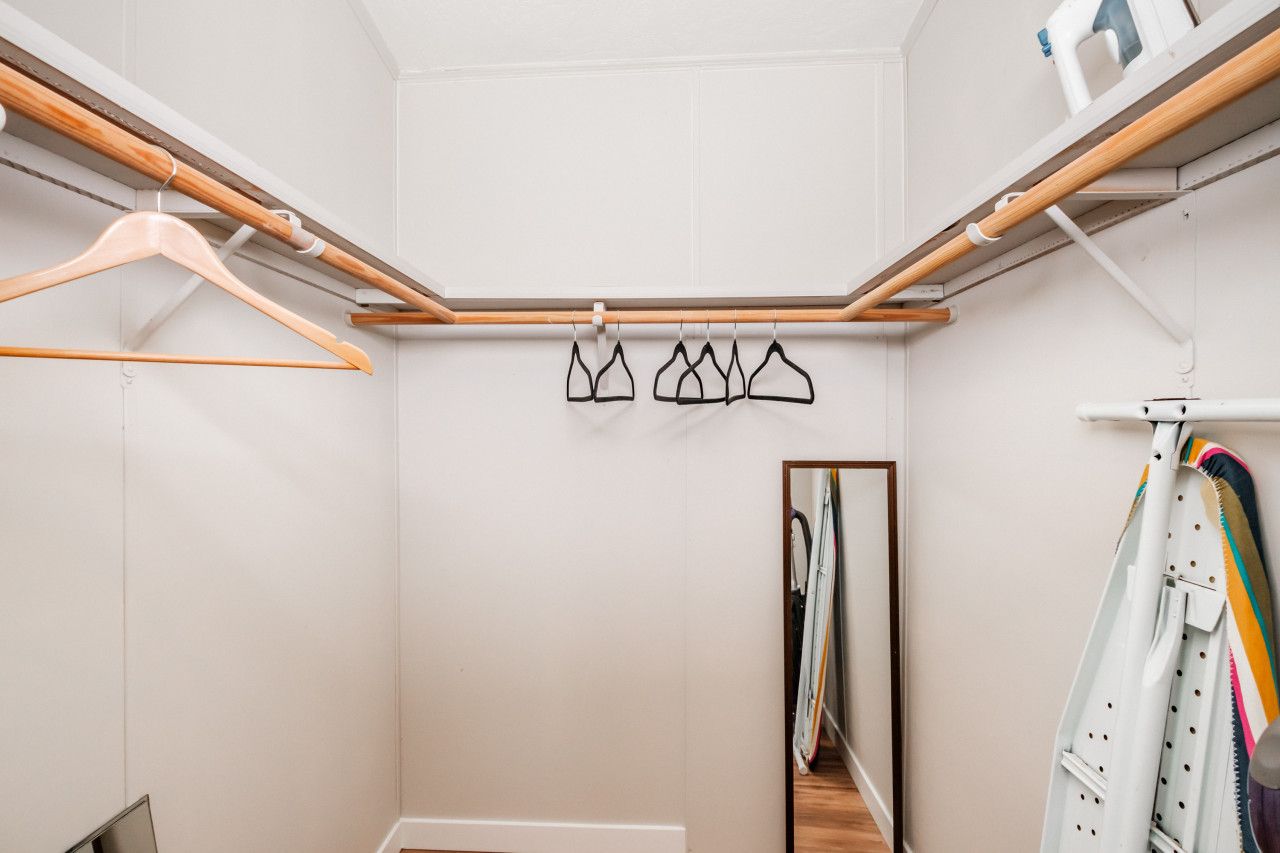 Un dressing avec des cintres en bois, un portant à vêtements et un miroir.