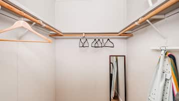 A walk-in closet with wooden hangers, a clothing rack, and a mirror.