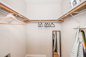 Un dressing avec des cintres en bois, un portant à vêtements et un miroir.