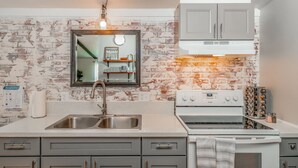 A kitchen with a brick backsplash, stainless steel sink, and white cabinets. - Escape to a beautiful country getaway (Philomath)