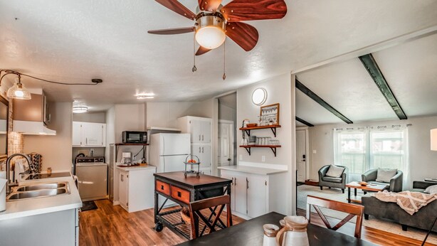 A modern kitchen with white cabinets, a dining area with a wooden table, and a ceiling fan. - Escape to a beautiful country getaway (Philomath)