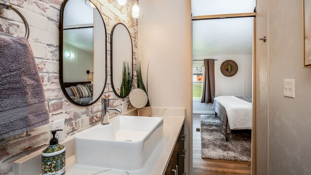 A bathroom with a white sink, two mirrors, and a brick wall. - Escape to a beautiful country getaway (Philomath)
