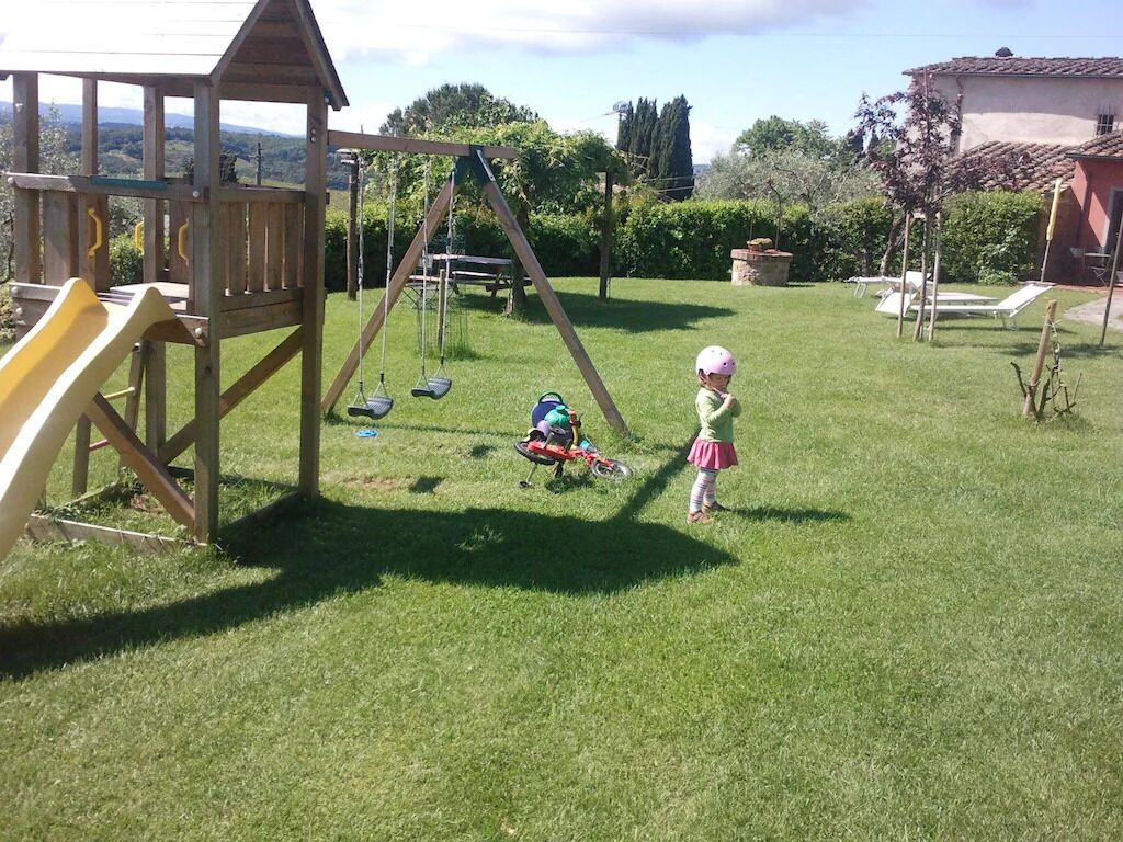 A wooden play structure with a slide and swings in a grassy backyard.