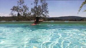 A person swimming in a clear pool with a view of trees and hills in the background. - Apartment House with garden Tuscany Chianti ,  Florence 15km. (Toscana)
