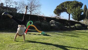 A child playing in a grassy area with a playground structure.