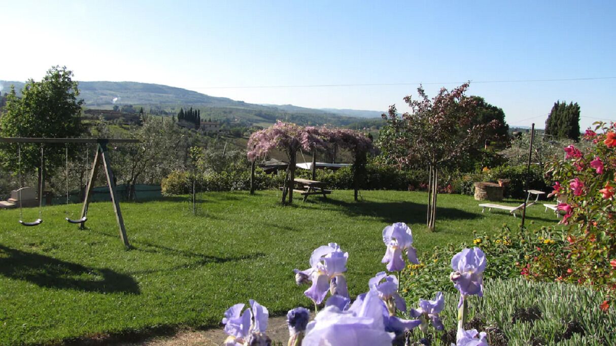 Um jardim com balanço, mesa para piquenique e flores desabrochando.