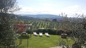 A garden with a lawn, three white lounge chairs, and a pergola. - Apartment House with garden Tuscany Chianti ,  Florence 15km. (Toscana)