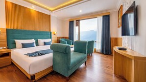 A hotel room with a large bed, two armchairs, a desk, and a TV. - Yashshree Sikkim Blossom 600 Meters From Mg Marg (Gangtok)