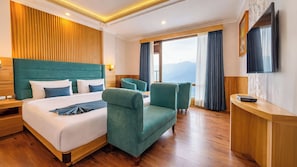 Une chambre d’hôtel avec un grand lit, deux fauteuils, un bureau et une télévision.