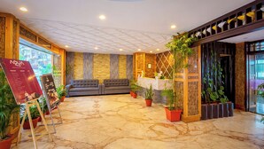 A hotel lobby with a marble floor, two grey sofas, a reception desk, and potted plants. - Yashshree Sikkim Blossom 600 Meters From Mg Marg (Gangtok)