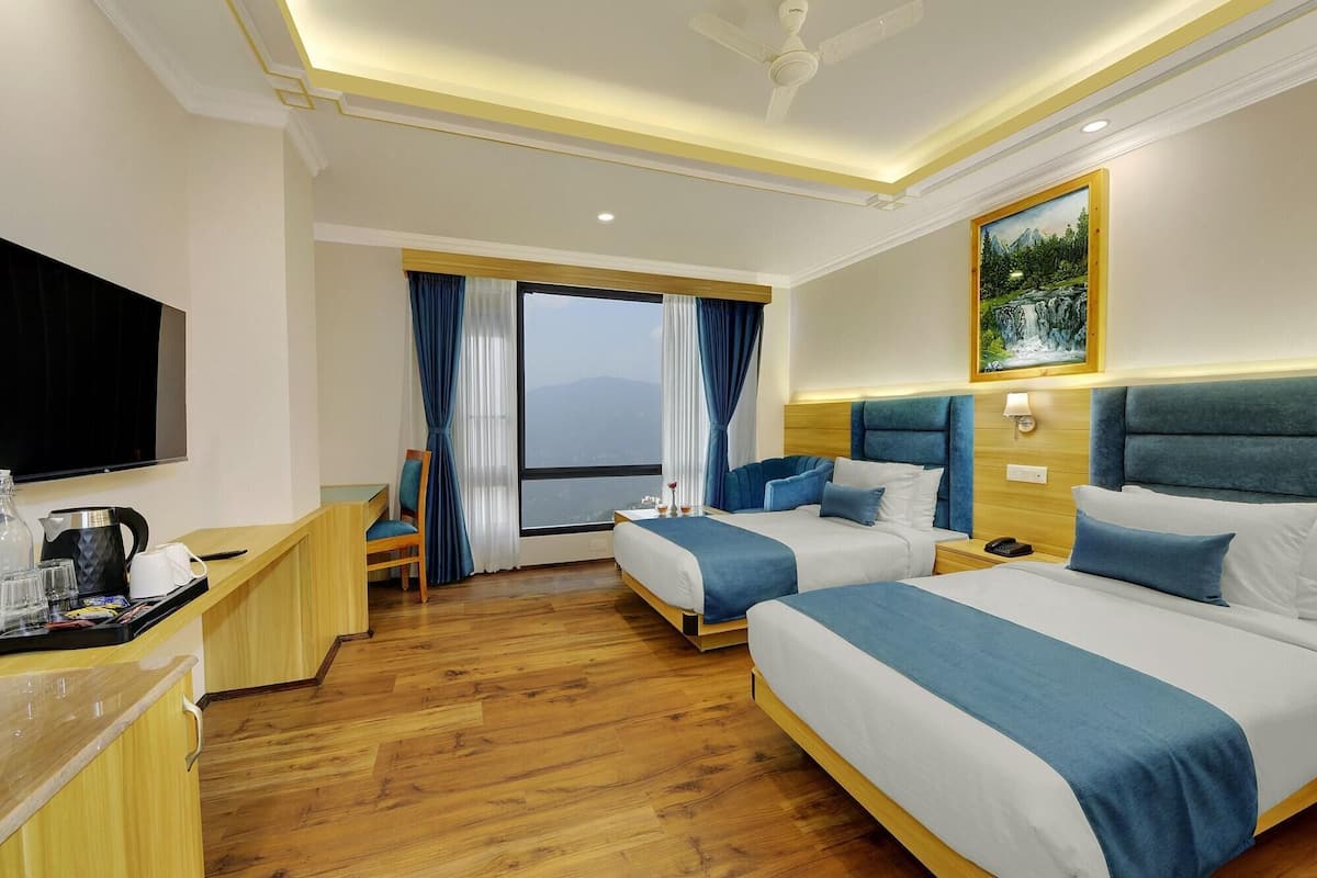 A hotel room with two beds, a TV, a desk with a coffee maker, and a window with a view.