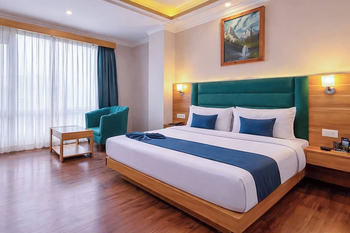 A hotel room with a bed, a desk, a chair, and a painting on the wall.