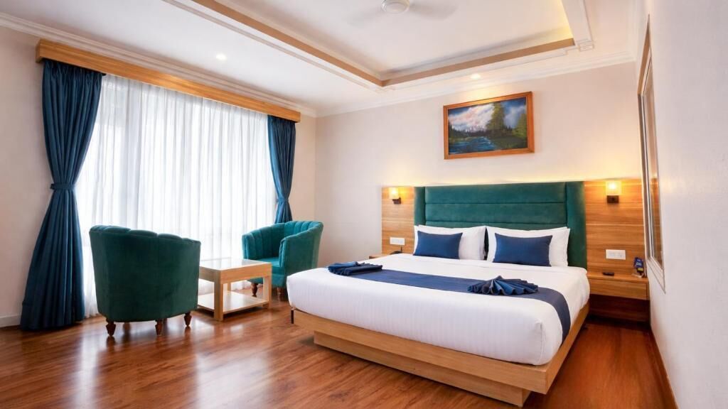 A hotel room with a bed, a desk, a chair, and a window with curtains.