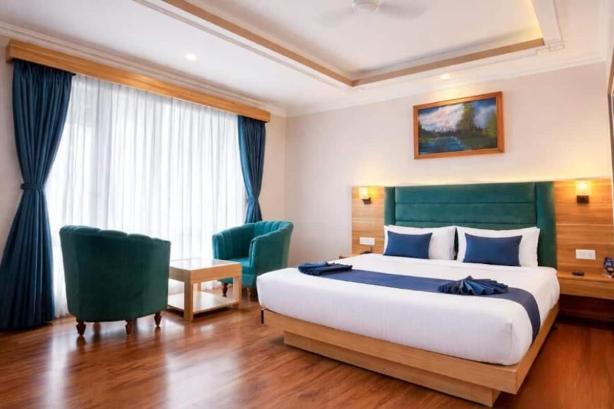 A hotel room with a bed, a desk, a chair, and a window with curtains.
