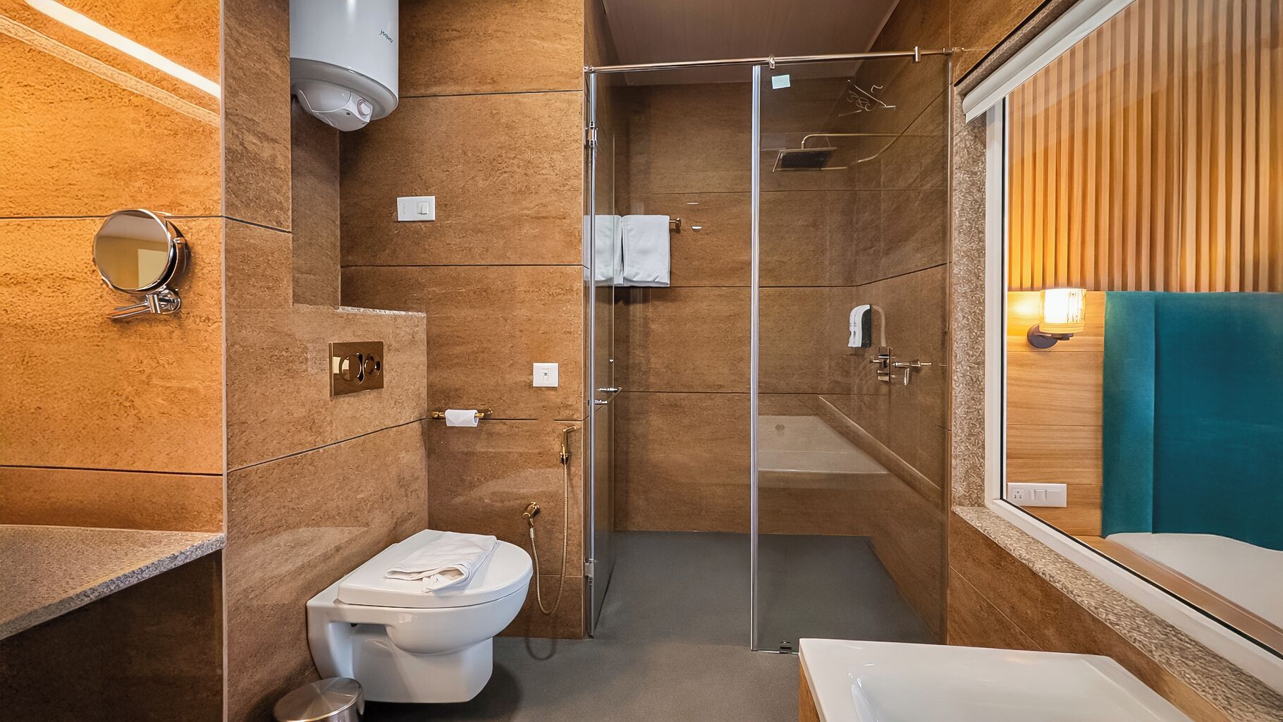 A bathroom with a toilet, a shower, a sink, a mirror, and a towel rack.