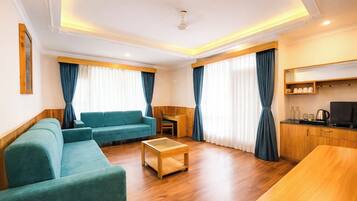 Una sala de estar moderna con un sofá, una mesa de centro y una zona de cocina con televisor y armarios.