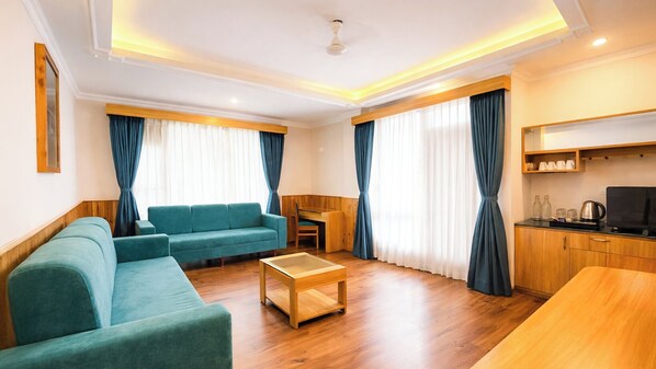 A modern living room with a sofa, a coffee table, and a kitchen area with a TV and cabinets.