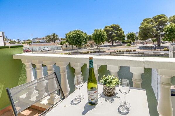 Ein Balkon mit einem Tisch für zwei Personen, einer Weinflasche und einer kleinen Pflanze.