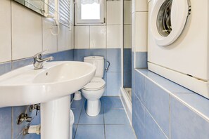 A bathroom with a sink, toilet, and washing machine.