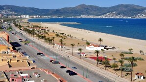 Una carretera costera con una playa y montañas al fondo.