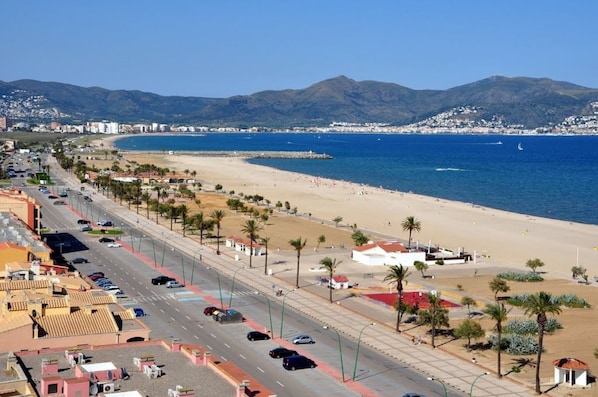 A coastal road with a beach and mountains in the background.