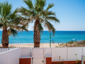 A beach view with palm trees and a white fence.