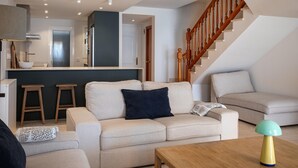 A modern living room with a sofa, a coffee table, and a staircase.