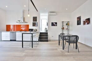 Une cuisine moderne dotée d’un îlot central, d’un coin repas avec une table et des chaises, et d’un escalier menant à un niveau supérieur.