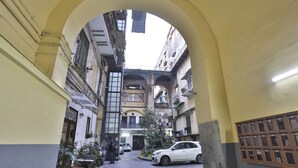 Un estrecho callejón con un coche blanco estacionado a la derecha, rodeado de edificios con balcones y ventanas.