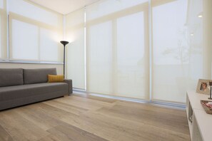 A modern living room with a sofa, a floor lamp, and large windows.