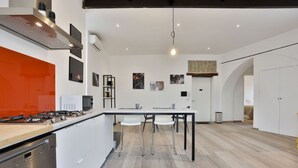 Una cocina moderna con una isla central, armarios blancos y una pared de acento naranja brillante.